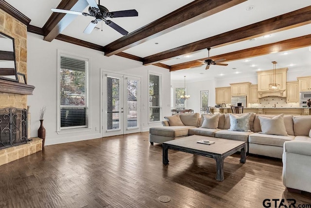 living room featuring beamed ceiling, dark hardwood / wood-style floors, a fireplace, and ceiling fan with notable chandelier