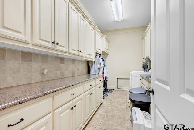 clothes washing area featuring cabinets, washer / dryer, crown molding, and light tile patterned flooring