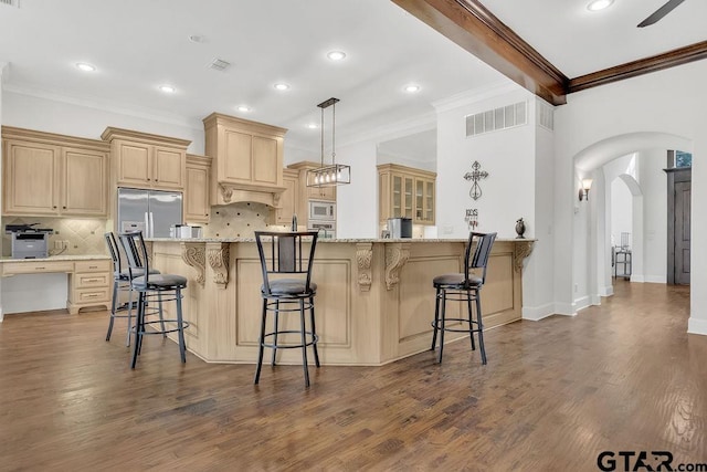 kitchen with tasteful backsplash, ornamental molding, white microwave, dark wood-type flooring, and a breakfast bar area