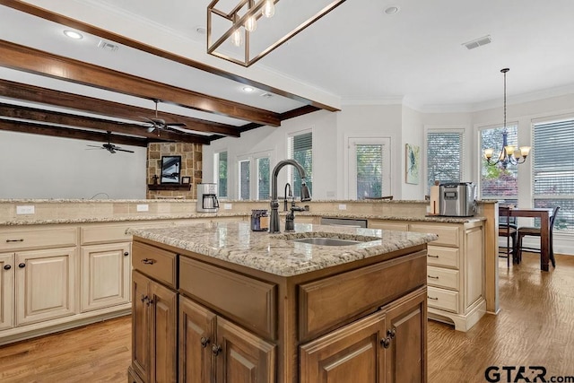 kitchen featuring sink, light hardwood / wood-style flooring, light stone countertops, an island with sink, and decorative light fixtures