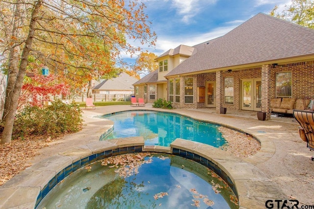 view of swimming pool with an in ground hot tub, a patio, and french doors