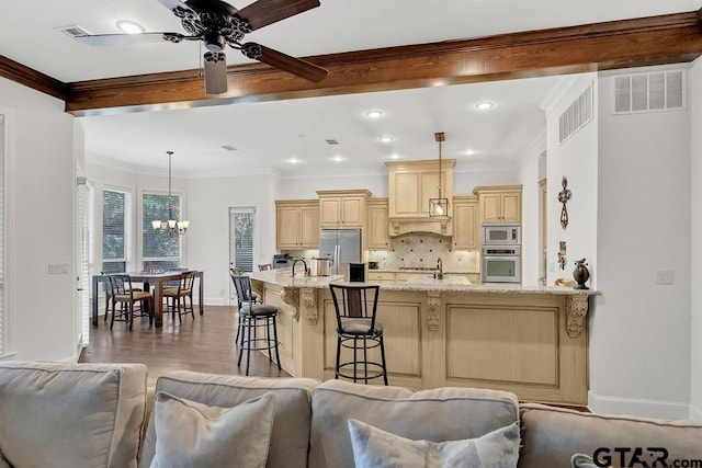 kitchen featuring light stone countertops, a kitchen breakfast bar, decorative backsplash, stainless steel appliances, and hanging light fixtures