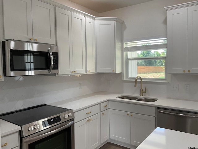 kitchen with backsplash, appliances with stainless steel finishes, sink, and white cabinets