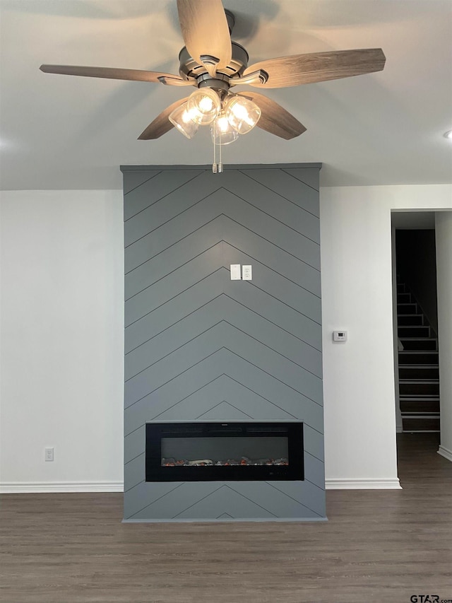 interior details with hardwood / wood-style floors, a large fireplace, and ceiling fan