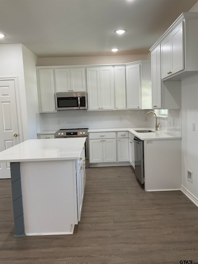 kitchen with stainless steel appliances, sink, white cabinets, dark wood-type flooring, and a center island