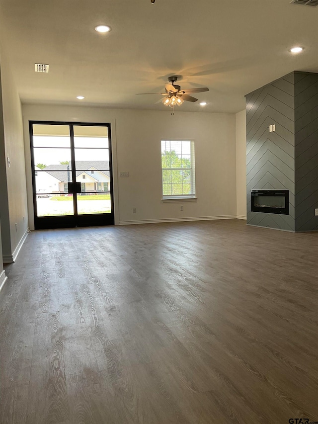 unfurnished living room featuring a large fireplace, hardwood / wood-style flooring, and ceiling fan