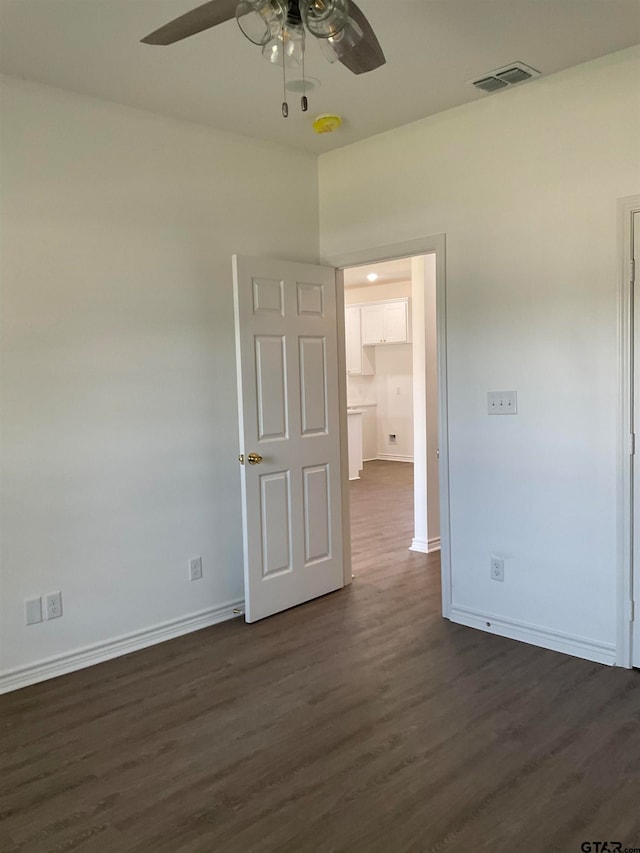 empty room with ceiling fan and dark hardwood / wood-style flooring