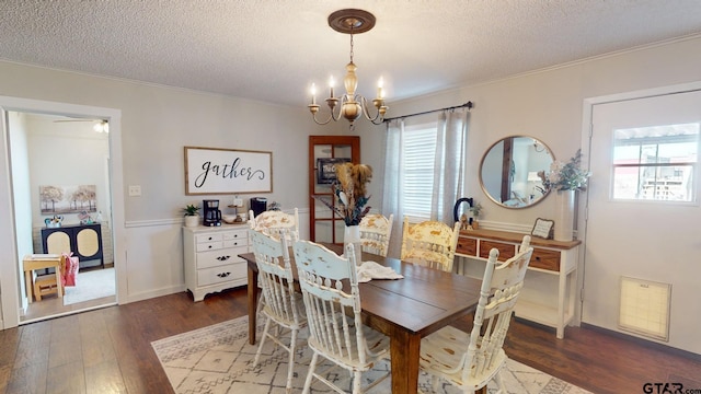 dining space featuring ornamental molding, ceiling fan with notable chandelier, dark wood-type flooring, and a textured ceiling