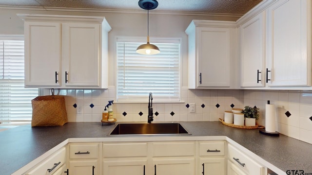 kitchen featuring white cabinetry, sink, and tasteful backsplash