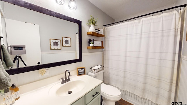 bathroom with toilet, a shower with curtain, vanity, and a textured ceiling