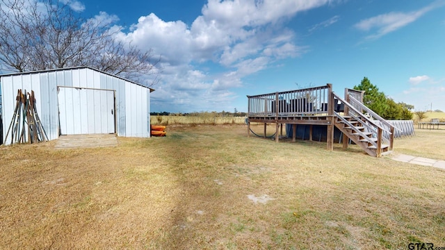 view of yard with a deck, an outbuilding, and a rural view