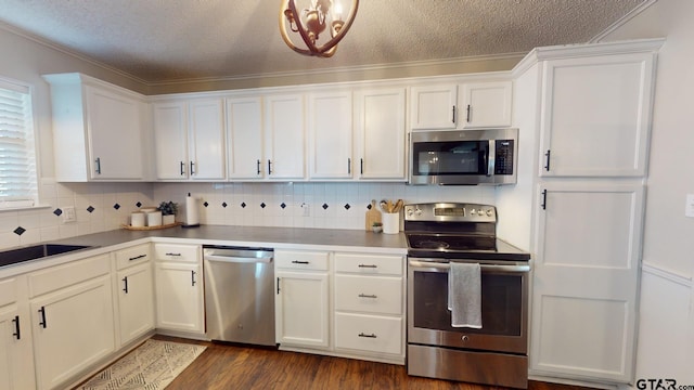 kitchen with dark hardwood / wood-style flooring, white cabinets, ornamental molding, and stainless steel appliances