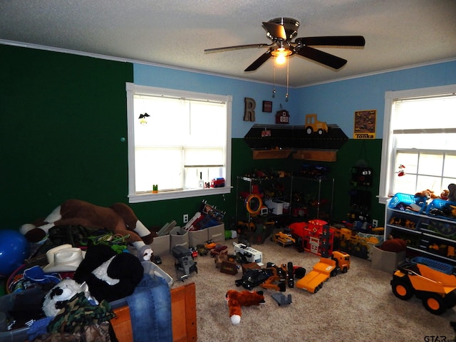 playroom featuring carpet, a textured ceiling, ceiling fan, and crown molding