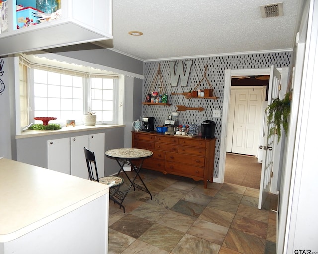 kitchen with white cabinetry, a textured ceiling, and crown molding