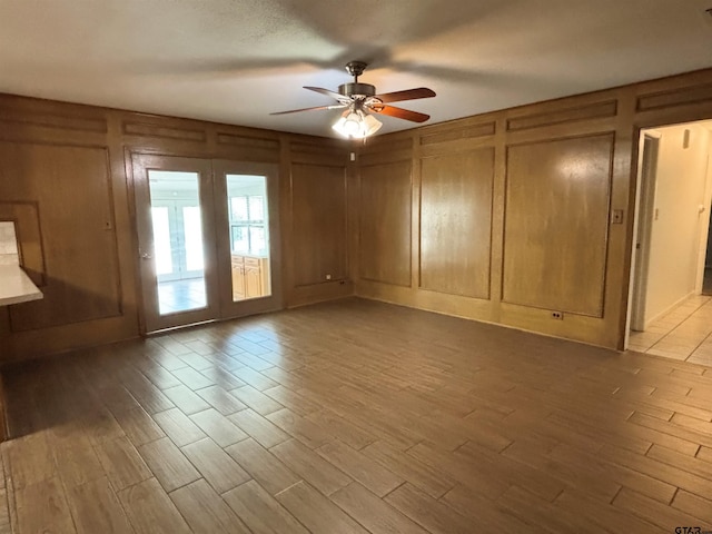 empty room with a decorative wall, a ceiling fan, and wood finished floors