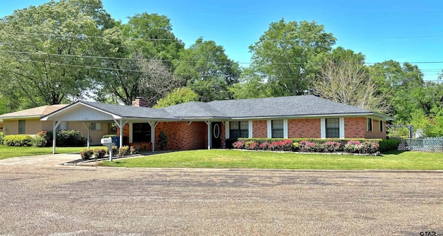 ranch-style house featuring a front yard, a chimney, fence, concrete driveway, and brick siding