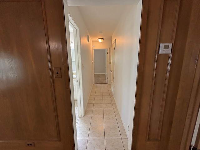 hall featuring light tile patterned floors and baseboards