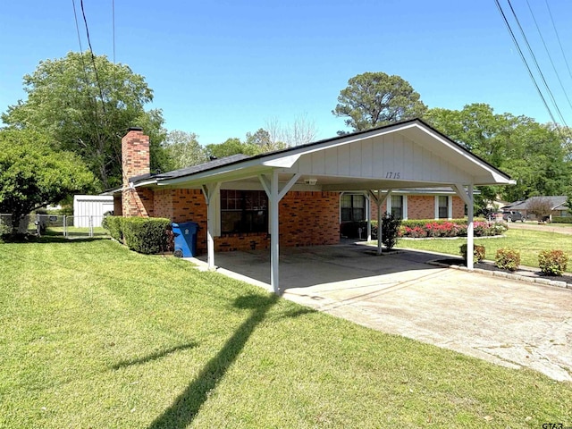 exterior space featuring a front yard, fence, brick siding, and driveway