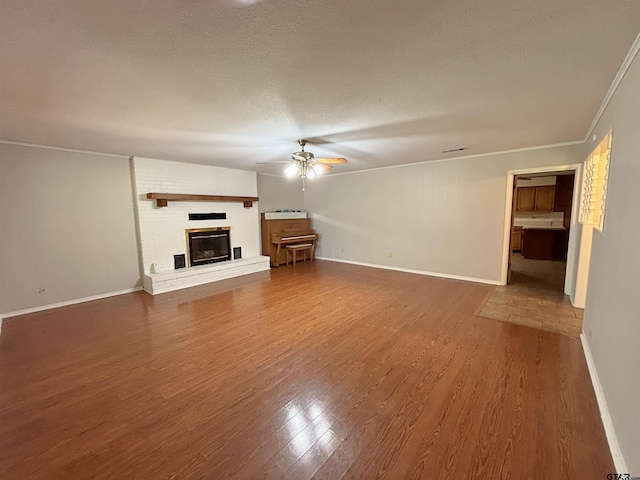 unfurnished living room with wood finished floors, ceiling fan, baseboards, and a brick fireplace