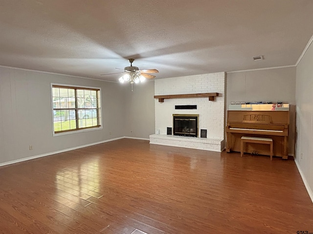 unfurnished living room featuring baseboards, crown molding, visible vents, ceiling fan, and wood finished floors