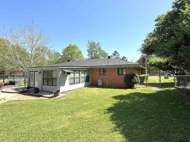back of house featuring brick siding, fence, a lawn, and a gate