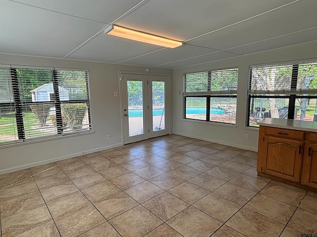 interior space with french doors, light tile patterned floors, and baseboards
