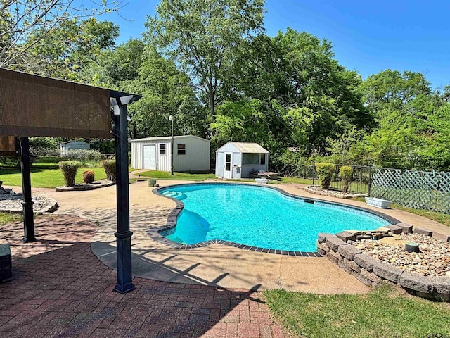 view of pool featuring an outbuilding, a storage shed, a patio, fence, and a fenced in pool