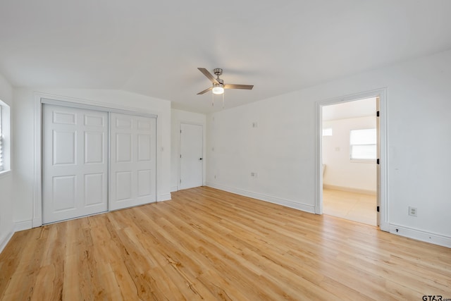 unfurnished bedroom with a closet, baseboards, ensuite bathroom, and light wood-style floors