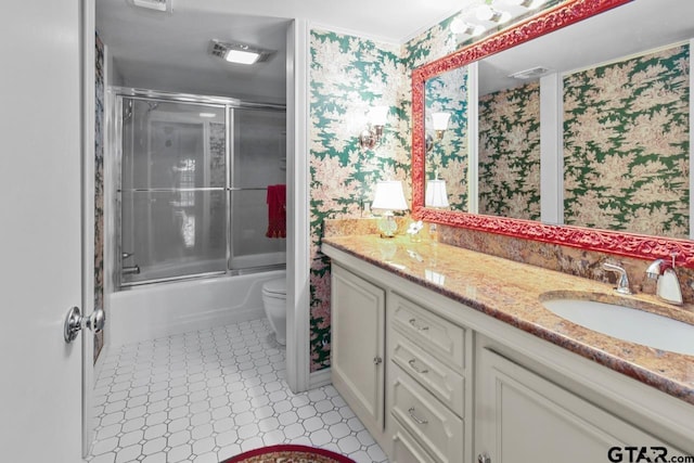 1719 S Chilton Ave, Tyler, TX 75701 - full bathroom featuring wallpapered walls, double vanity, toilet, and bath / shower combo with glass door