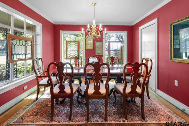 dining space with hardwood / wood-style floors, ornamental molding, a healthy amount of sunlight, and a notable chandelier