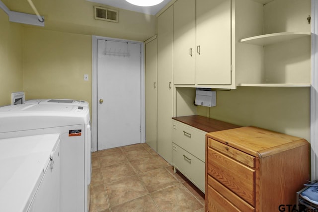 clothes washing area featuring washing machine and dryer, light tile patterned floors, and cabinets