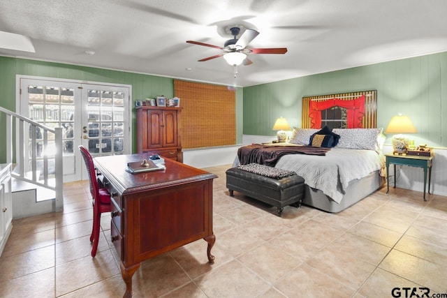 tiled bedroom with ceiling fan, french doors, and a textured ceiling