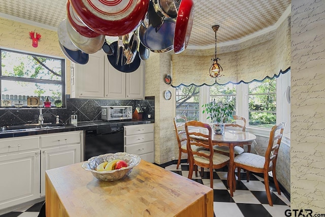 kitchen featuring white cabinets, sink, ornamental molding, black dishwasher, and plenty of natural light