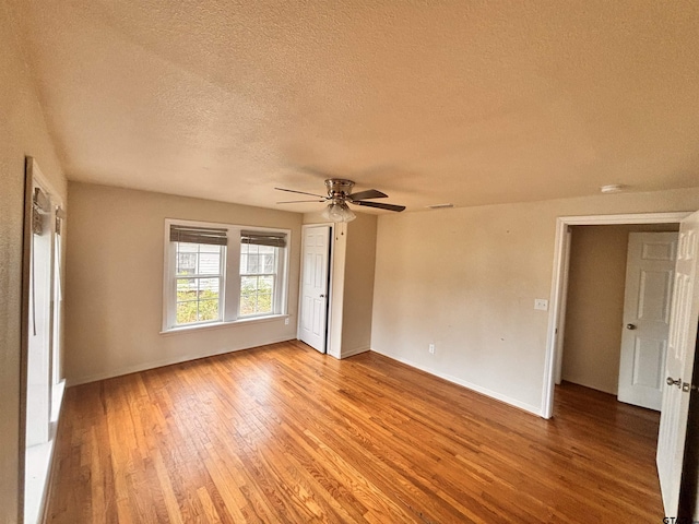 spare room with hardwood / wood-style flooring, ceiling fan, and a textured ceiling