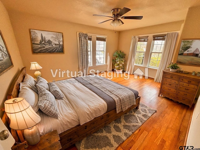 bedroom with ceiling fan, a textured ceiling, and light hardwood / wood-style floors