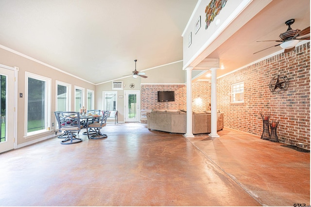 living room with decorative columns, concrete floors, and brick wall