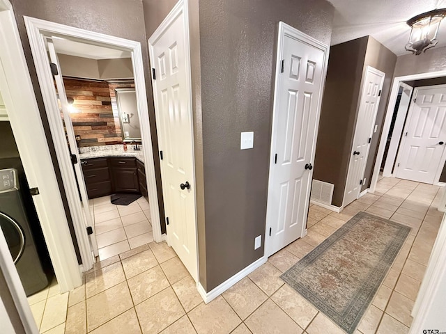 18872 Big Timber Rd, Tyler, TX 75703 - hallway featuring washer / dryer, light tile patterned floors, and a textured wall