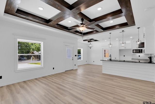 unfurnished living room with coffered ceiling, a wealth of natural light, beam ceiling, and light hardwood / wood-style flooring