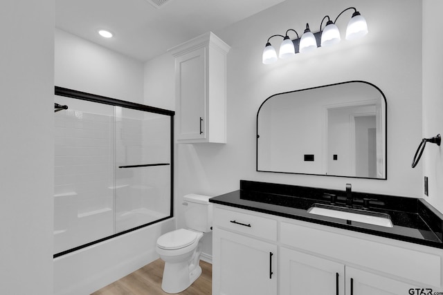 full bathroom featuring toilet, vanity, bath / shower combo with glass door, and wood-type flooring