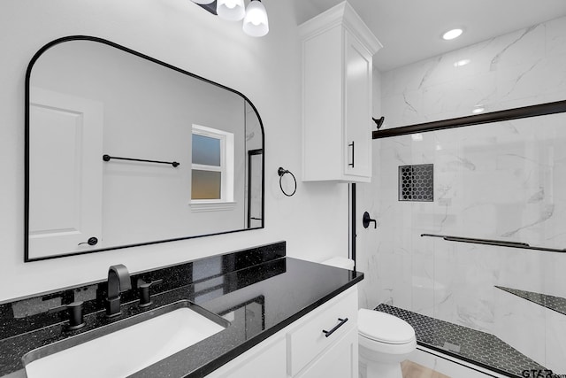 bathroom featuring a shower with door, vanity, and toilet