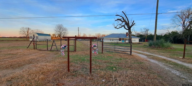 view of gate with fence, a yard, and a rural view