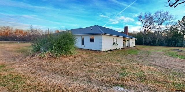 view of side of home with a yard, a chimney, and metal roof