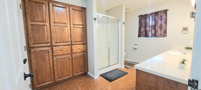 full bath with vanity, wood finished floors, toilet, baseboards, and a stall shower