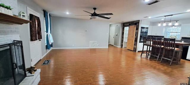 living room with ceiling fan, a fireplace with raised hearth, and visible vents
