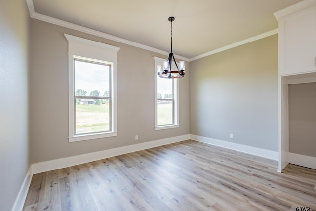 spare room featuring ornamental molding, baseboards, light wood-type flooring, and a chandelier