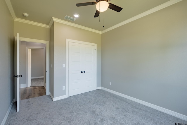 unfurnished bedroom featuring baseboards, ornamental molding, visible vents, and carpet floors