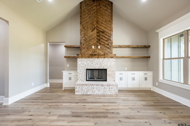 unfurnished living room with high vaulted ceiling, a fireplace, light wood-style flooring, and baseboards