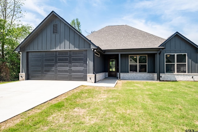view of front of home featuring board and batten siding, roof with shingles, a front yard, an attached garage, and driveway