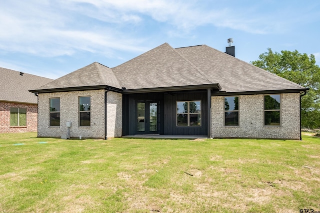 back of house with roof with shingles, a yard, and a chimney