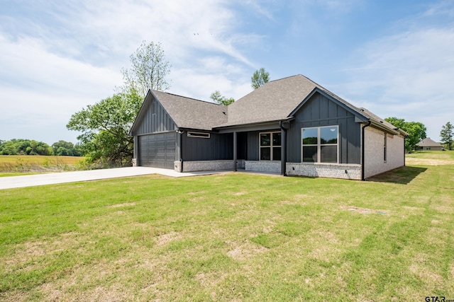 view of front of home featuring board and batten siding, roof with shingles, a front yard, an attached garage, and driveway